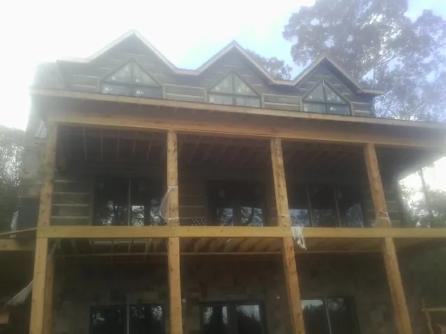 Dormers and porch framing on a large log home under construction — Roof Coating work by our crew in Springtown