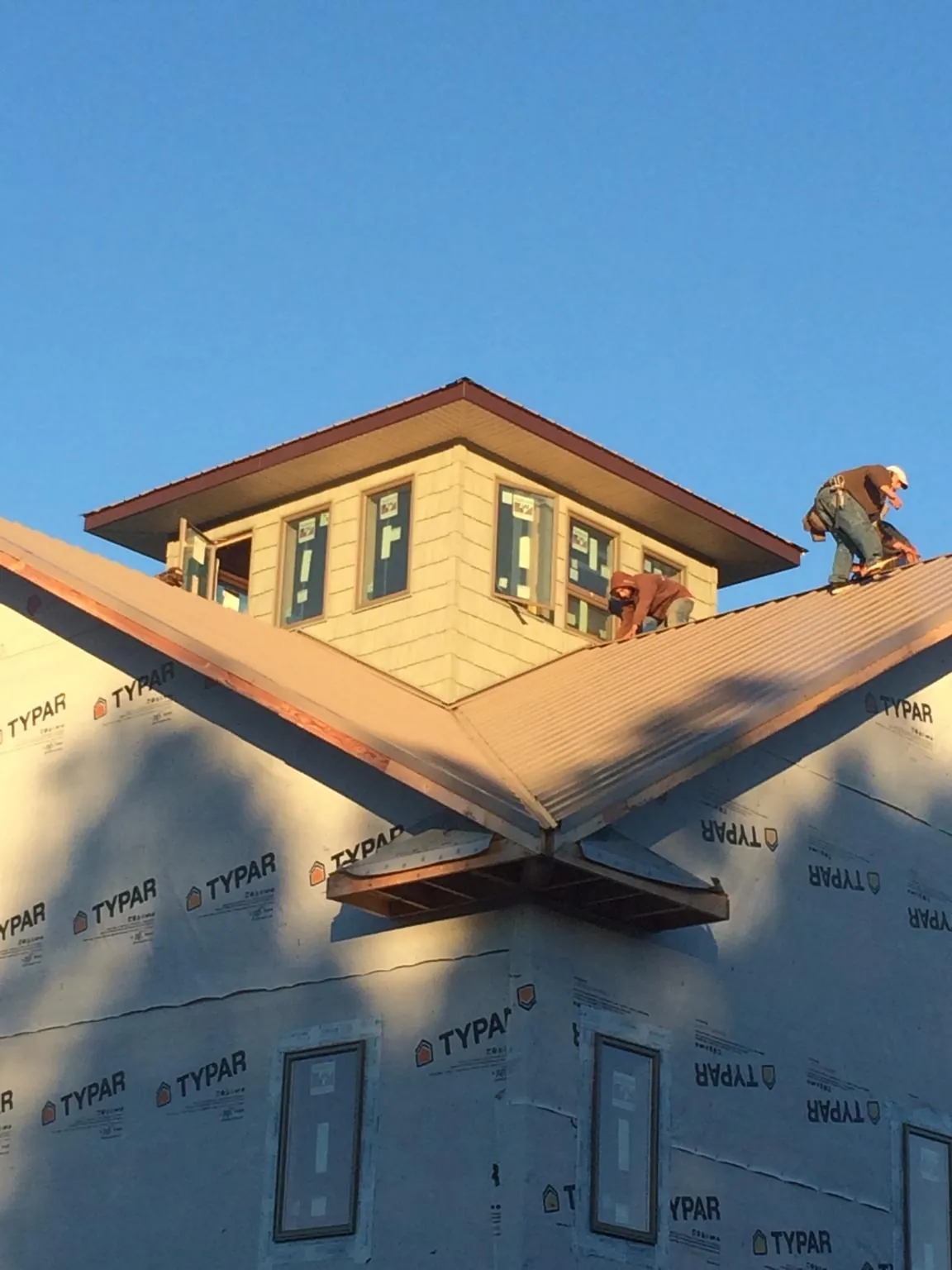Roofers working around a rooftop cupola on a new metal roof at sunset — Roof Waterproofing in Springtown by Roofing Brothers